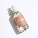 Clear spray bottle with a pink label on a white background