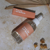 Palm Springs room spray and perfume roller on a textured surface with dried flowers.