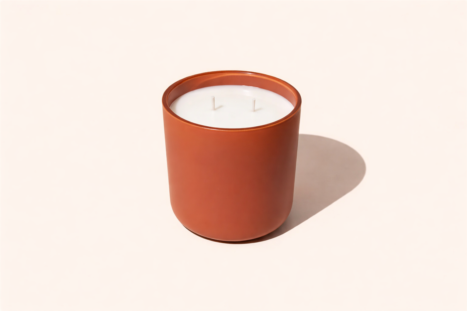 Candle in a terracotta jar on a light beige background
