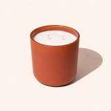 Candle in a terracotta jar on a light beige background