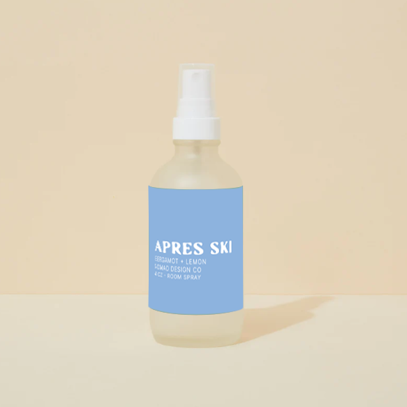 Bottle of 'Apres Ski' room spray with a blue label on a beige background