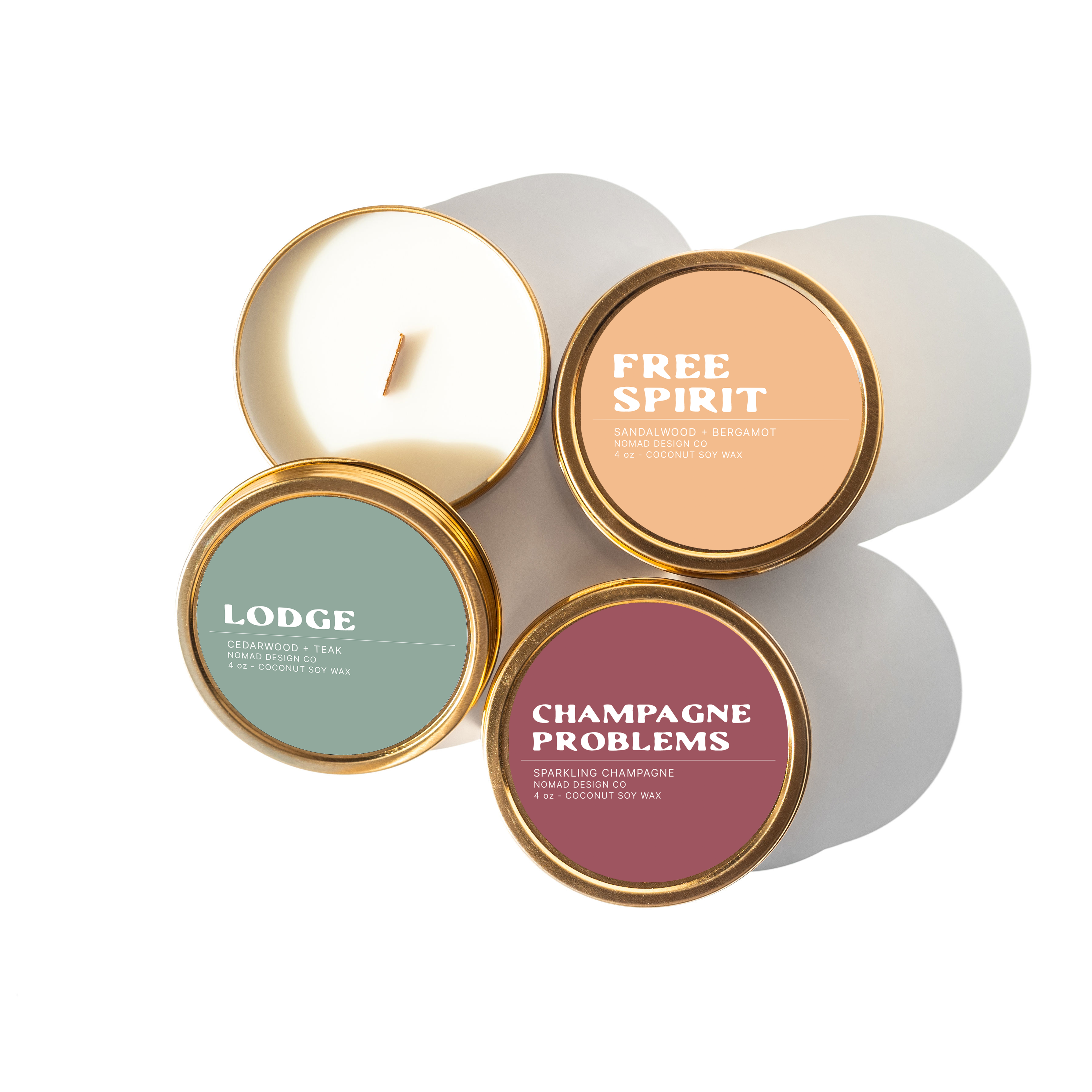 four travel tin candles with 'free spirit', 'lodge', and 'champagne probelms' labels