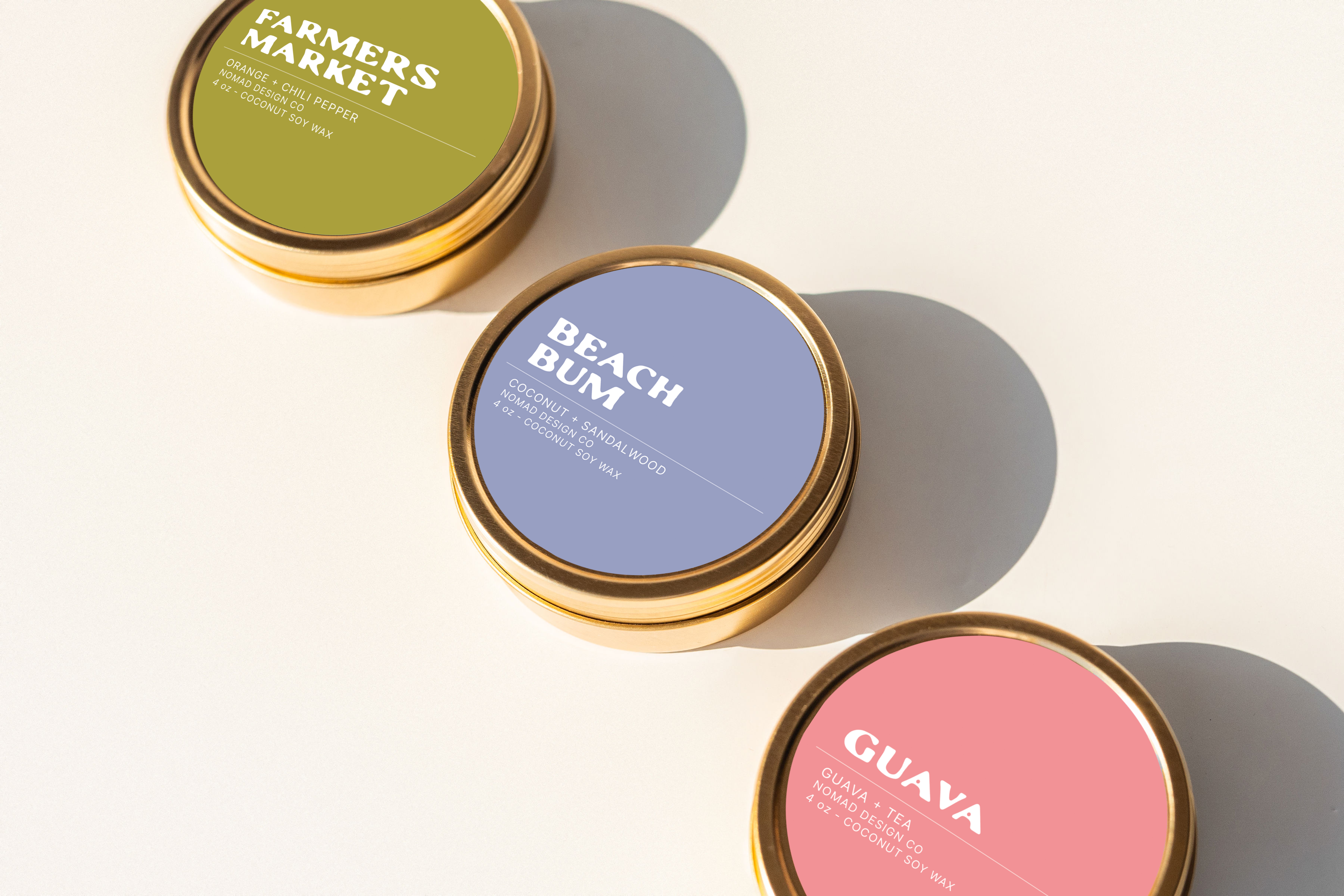 Three summer-inspired travel tin candles labeled 'Farmers Market', 'Beach Bum', and 'Guava'.