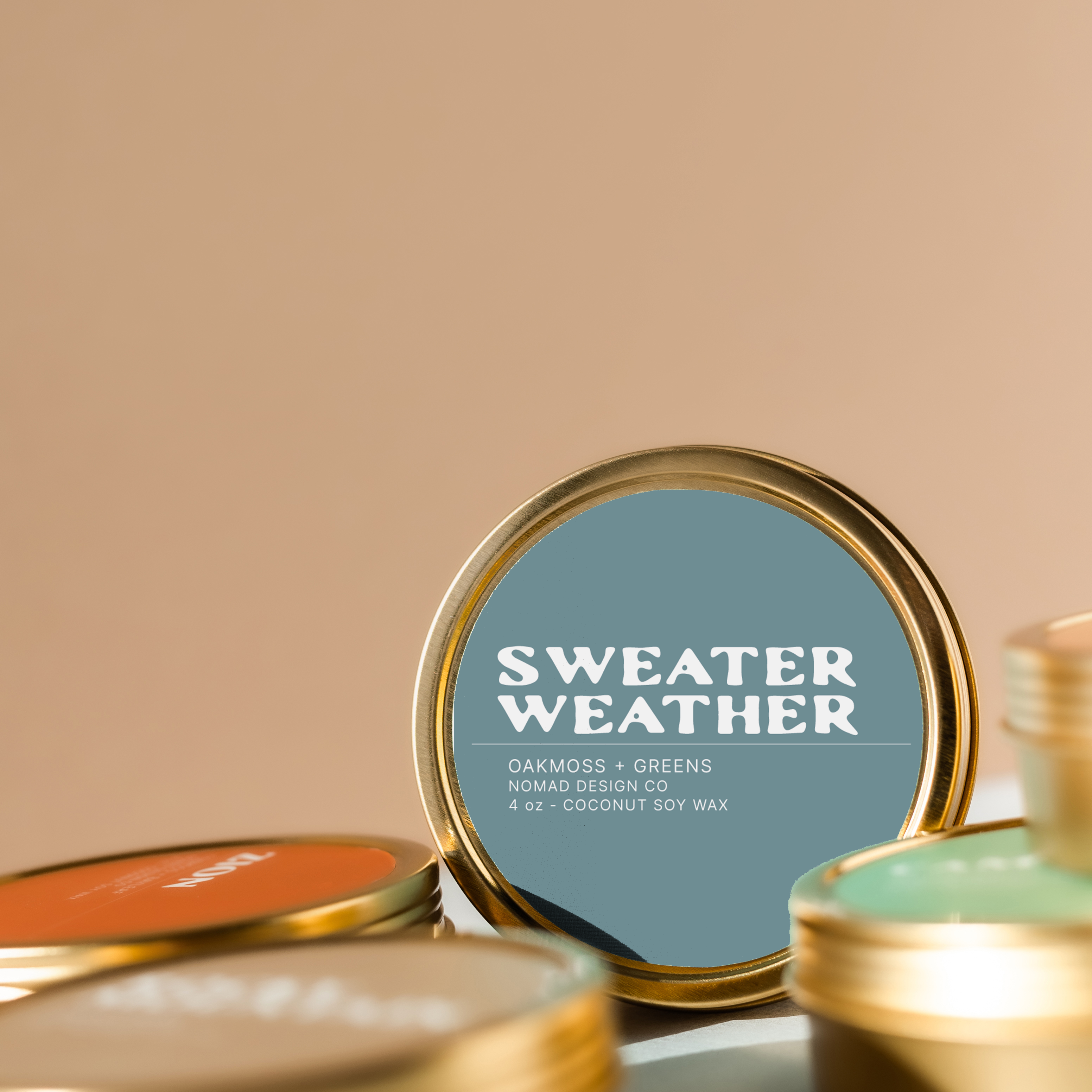 Gold tins with 'Sweater Weather' label on a beige background