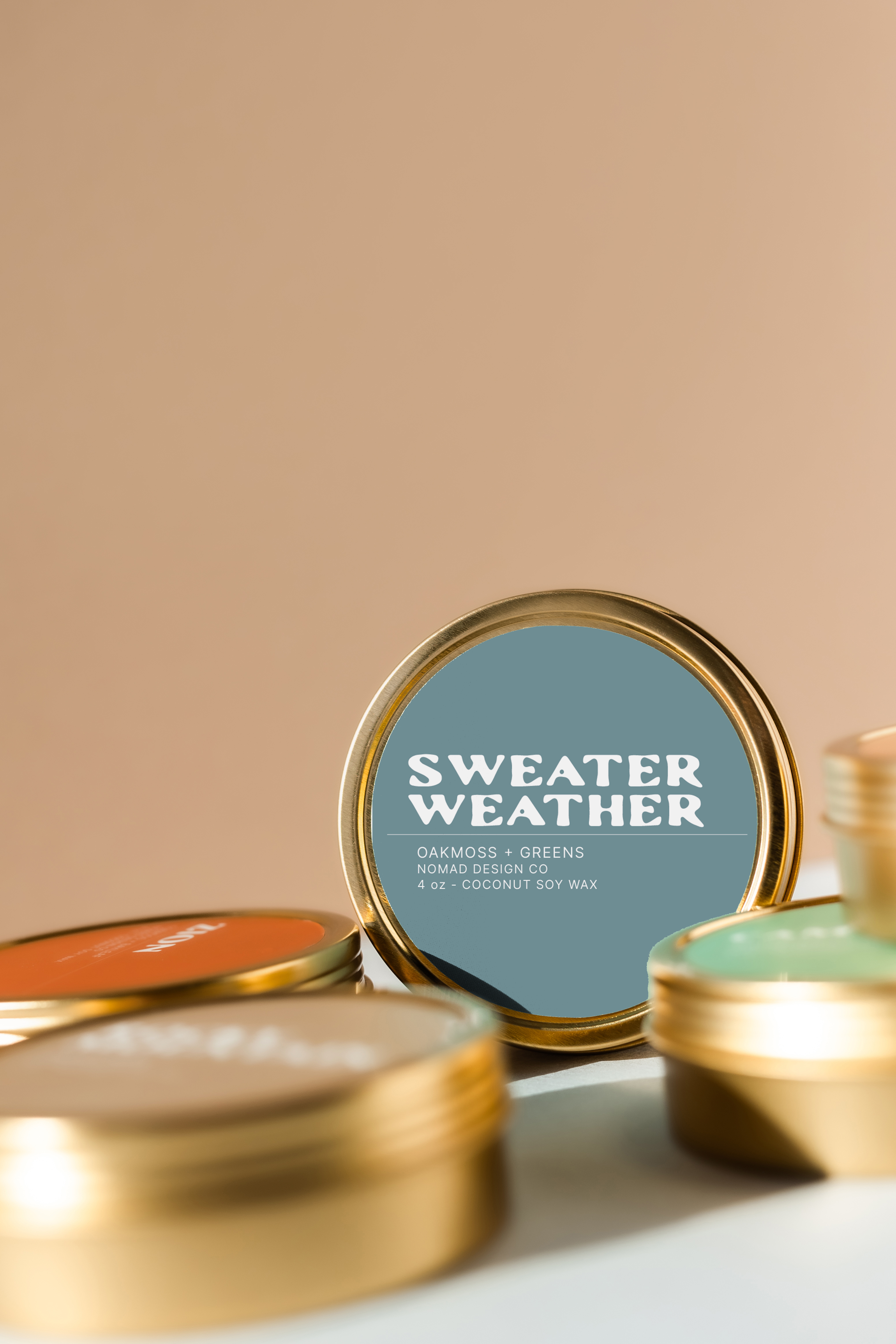 Gold tins with 'Sweater Weather' label on a beige background